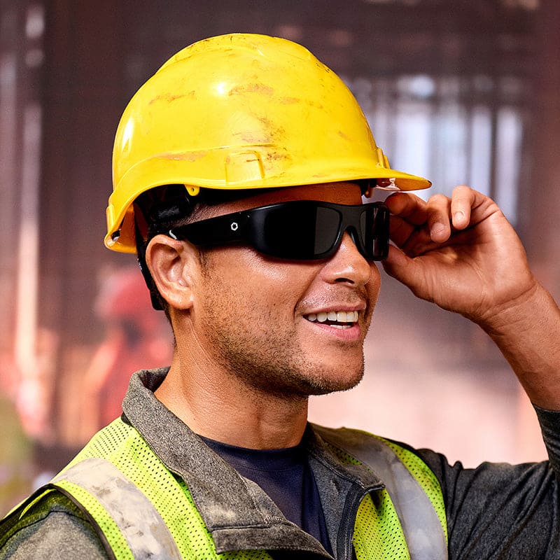 Smiling construction worker adjusting Lucyd Armor Black Polarized sunglasses with hard hat