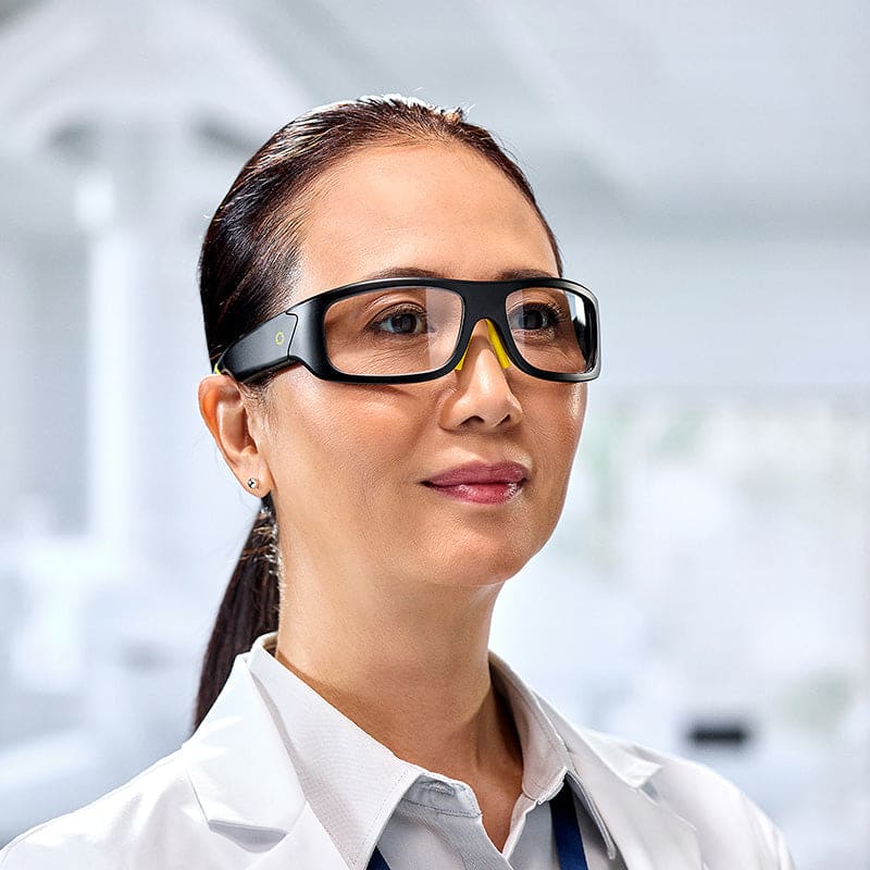 Woman in white lab coat wearing Lucyd Armor Slim Photochromic glasses in laboratory