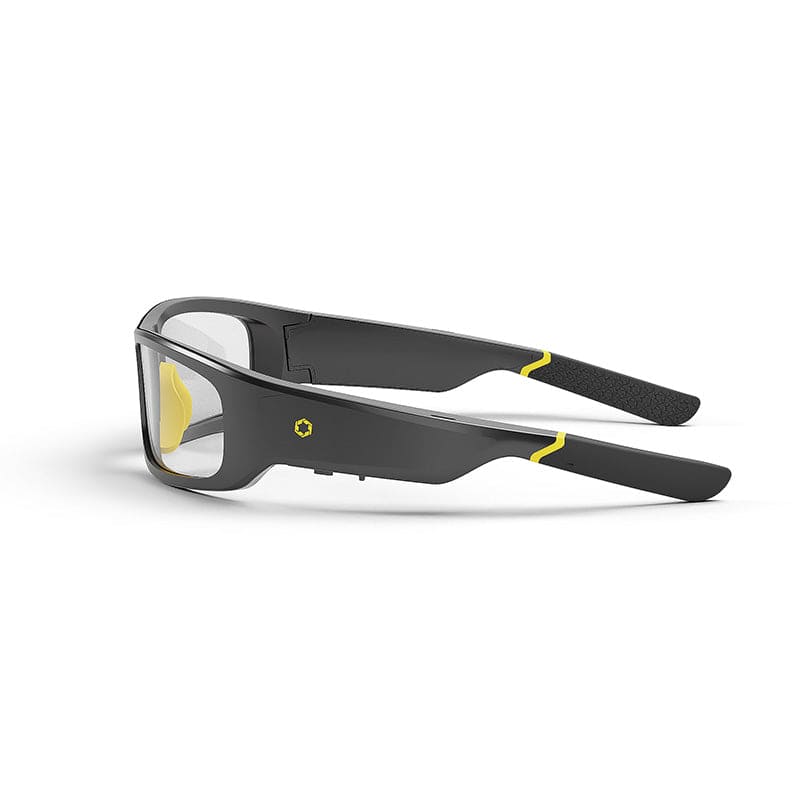 Lucyd Armor | Slim Photochromic smart glasses feature transparent lenses and yellow accents on black frames. ANSI Z87.1 certified, they offer advanced protection and stylish design while resting folded on a white surface.