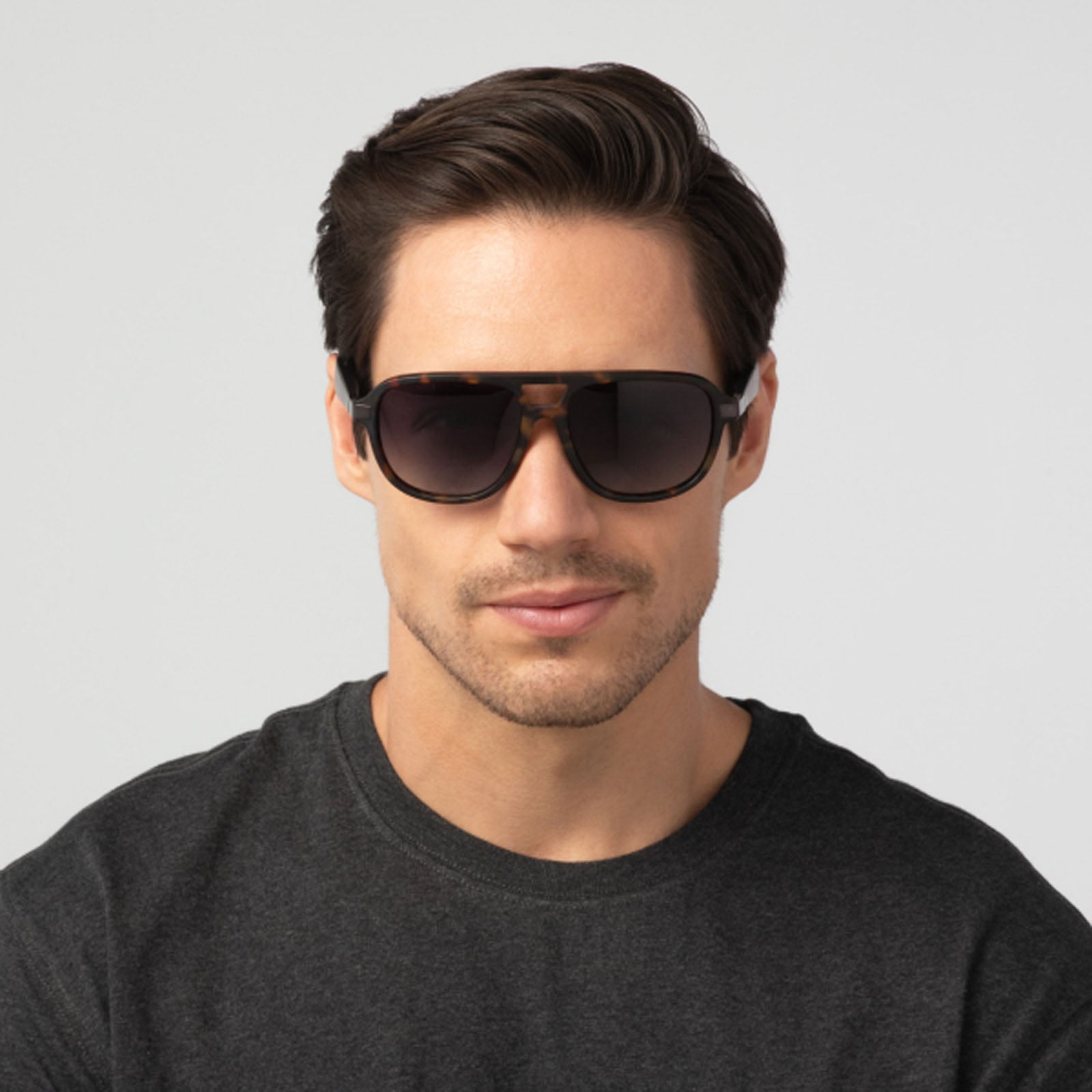 A man with short dark hair, wearing a dark t-shirt and Eddie Bauer Explorer polarized UV400 sunglasses, stands against a plain light background facing forward with a neutral expression.