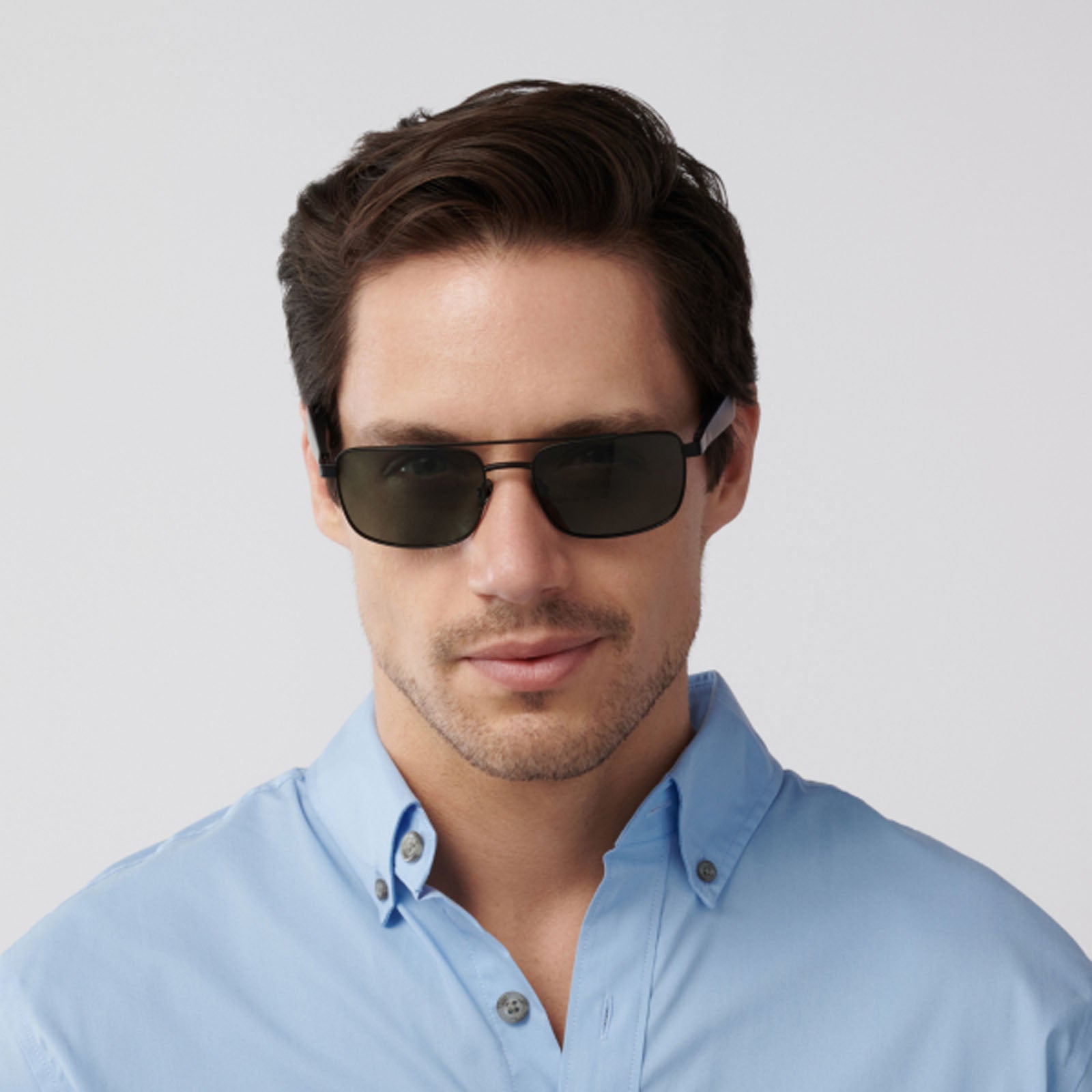 A man with short brown hair wears Eddie Bauer Navigator UV400 polarized sunglasses and a light blue button-up shirt, facing forward against a plain light gray background.
