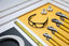 The LUCYD EYEWEAR Armor Pro Pack, including safety glasses, wrenches with yellow handles, PVC pipes and fittings, a flexible hose, and a measuring tape, is neatly arranged on a yellow and white background.