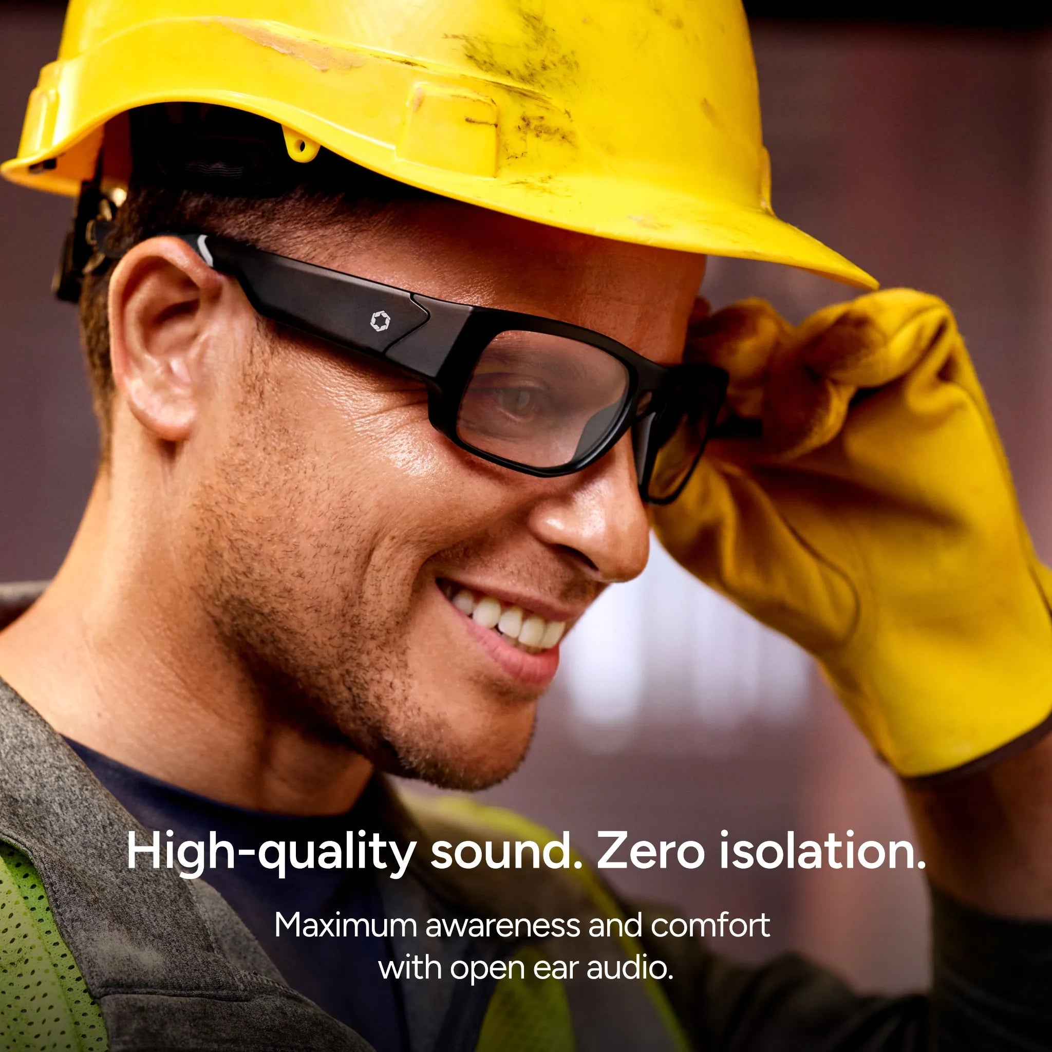 A smiling worker wears Lucyd Armor | Vantage Photochromic smart safety glasses by Lucyd, a yellow hard hat, protective glasses, and yellow gloves. Text on image: High-quality sound. Zero isolation. Maximum awareness and comfort with open ear audio.